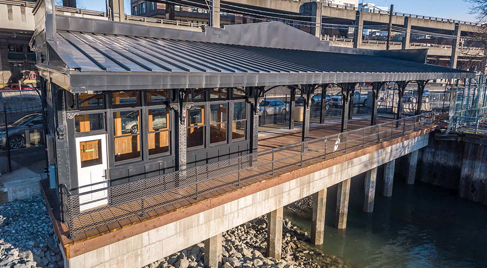 Photo of the reinstalled Washington Street Boat Landing Pergola, an outdoor structure consisting of columns that support a roofing grid of beams and rafters that is located by the water at the end of South Washington Street