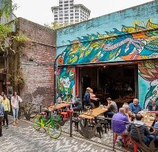 People enjoying food while sitting outdoors in a colorful Pioneer Square alley
